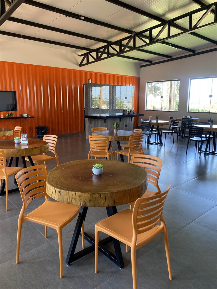 Restaurante com mesas de tronco e cadeiras laranja